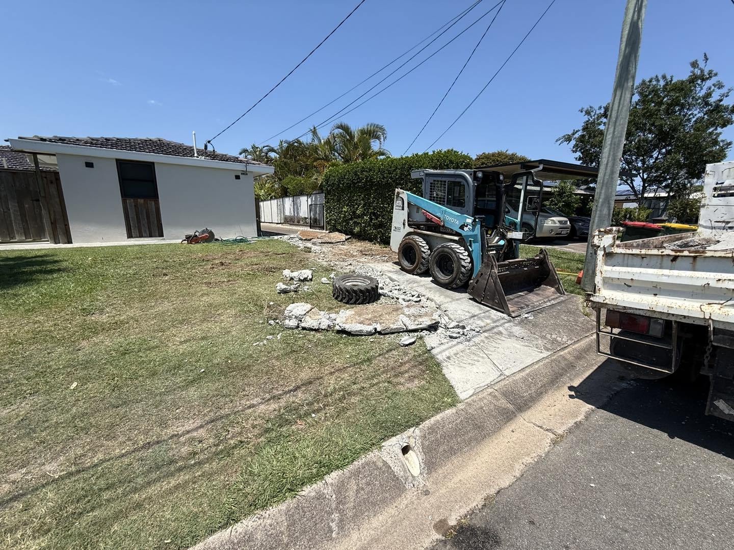 Bobcat loading broken concrete during driveway demolition