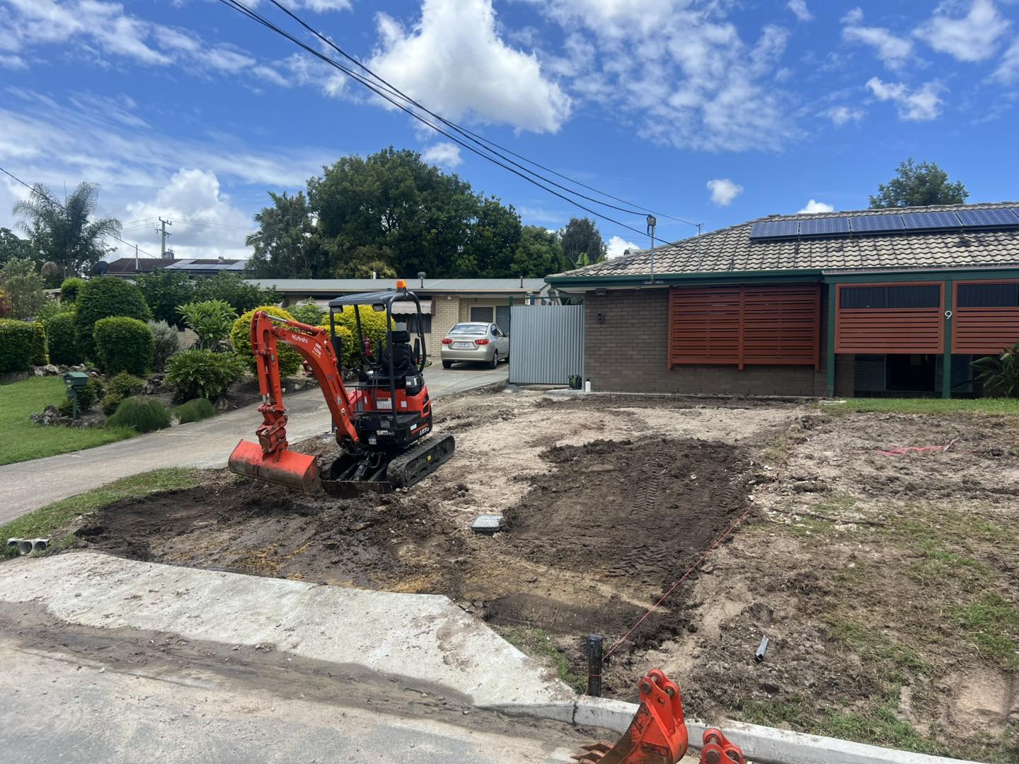 Mini excavator stripping front yard for new driveway