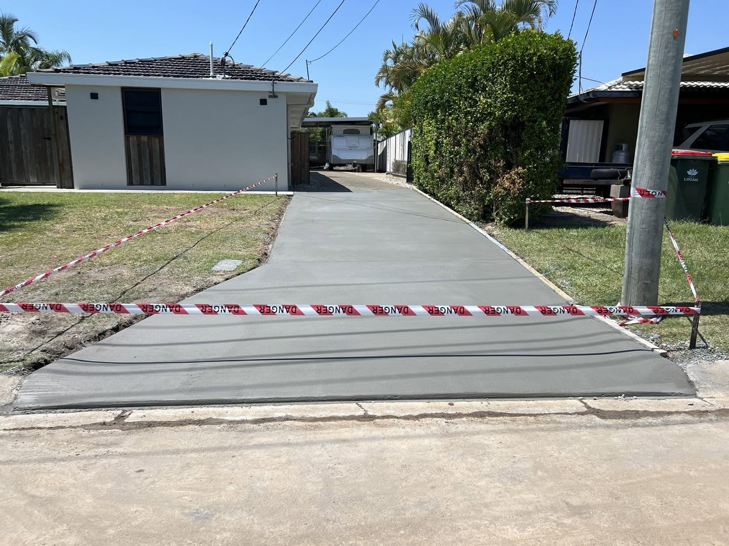 Freshly poured plain concrete driveway with danger tape
