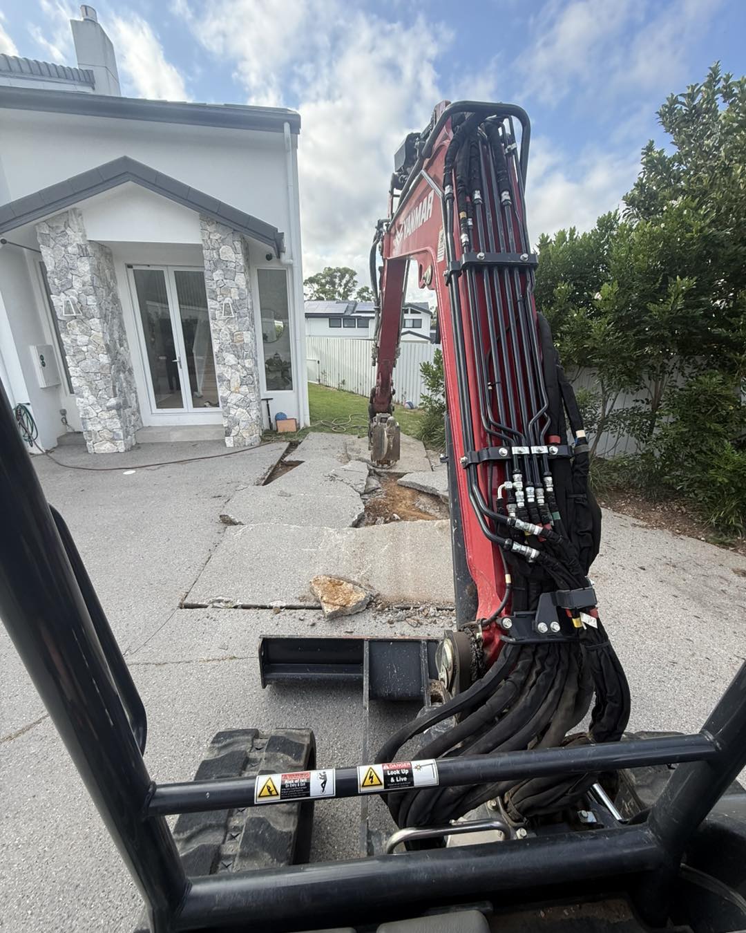 Breaking old concrete patio with excavator